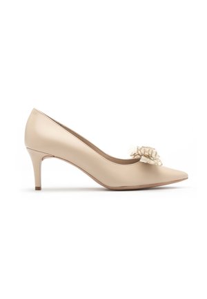 Beige patent leather high-heeled pump with pointed toe, featuring a lace floral accent on the vamp. Stiletto heel approximately 3 inches.