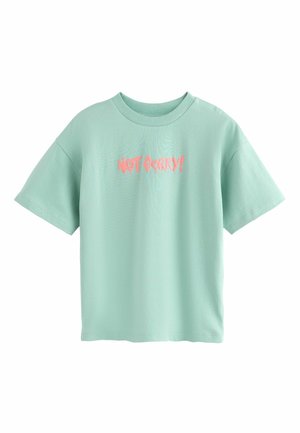 Mintgrøn T-shirt med korte ærmer, ribbet rund halsudskæring og pink tekst "NOT SORRY!" trykt i midten.