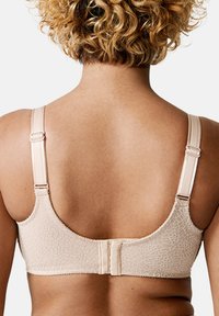Beige bra with textured pattern, adjustable straps, and hook closure. Smooth fabric and curved edges enhance fit and comfort.