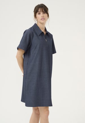 Marineblå kjole med kort ærme og lynlås krave, der har en afslappet pasform og glat, struktureret stof. Enkel, minimalistisk design med sidelommer.