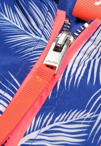 Blått tyg med mönster av vita palmblad, med en glänsande silverdragkedja och en klar neonrosa dragkedjesnor.