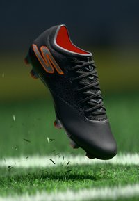 Ciorap de fotbal negru cu un material texturat, logo portocaliu și căptușeală roșie în contrast. Cuie concepute pentru aderență pe suprafețe de iarbă.