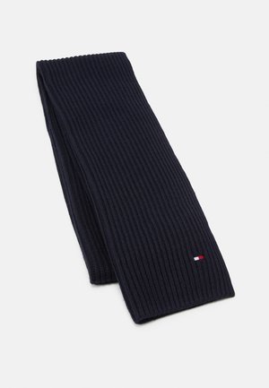 Granatowy szalik z dzianiny prążkowanej, złożony, z małym prostokątnym logo w kolorach czerwonym, białym i niebieskim przy jednym końcu.