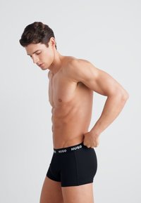 Boxer shorts negros con un ajuste ceñido, fabricados con un tejido suave, que presentan un logo blanco en contraste en la cinturilla.