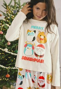 Kremowy długi rękaw z kolorowymi świątecznymi nadrukami zwierząt i napisem "WESOŁE SQUISHMAS!" W komplecie ze spodniami piżamowymi z podobnymi wzorami.
