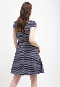 Vestido azul marino con patrón de lunares, mangas cortas y cintura ajustada. Incluye un cinturón marrón, falda acampanada y textura suave.