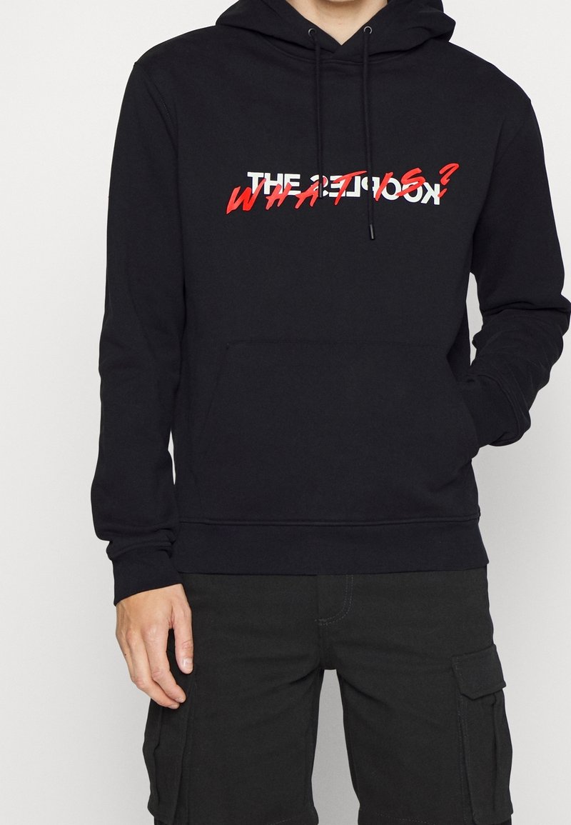 Sudadera con capucha negra y bolsillo frontal; presenta un diseño de texto audaz en blanco y rojo. Tejido suave, mangas largas, ajuste casual.