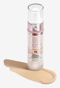 Langzeit-Make-up in einer klaren Pumpflasche, mit einem rosa Etikett mit "F5", neben einem Streifen hellbeiger Flüssigkeit auf einem weißen Hintergrund.