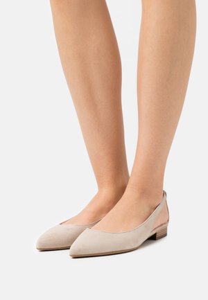 Ballerines en suède beige avec un bout pointu, un petit talon en bois et des côtés découpés révélant une touche de peau. Texture lisse et design minimaliste.