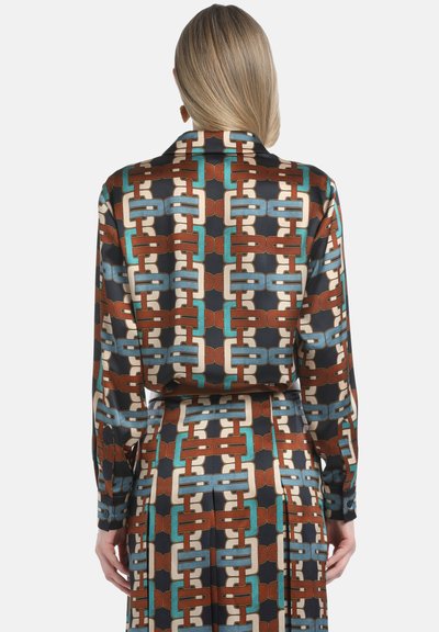 Silkkinen kangasmekko, jossa on geometrinen ketju-kuvio ruskeassa, tealissa ja kermanvärisessä, varustettuna kauluksella ja pitkillä hihoilla.