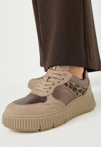 Sneaker beige con un mix di materiali scamosciati e lisci, caratterizzati da un pannello con stampa leopardata, suole spesse a coste e design con lacci.