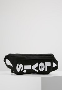 Svart tyg midjeväska med justerbar rem och stora vita bokstäver som delvis stavar "Levi's" på framsidan.