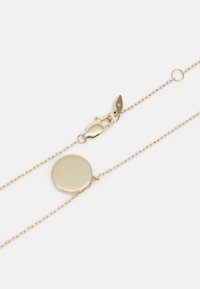 Collier en chaîne dorée avec un pendentif rond et un fermoir à mousqueton. Le pendentif a une surface lisse et réfléchissante.