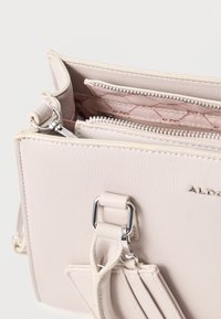 Light pink leather handbag with a structured shape, zippered compartments, and silver-tone hardware. Interior features a quilted pattern.