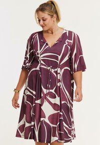 Lilla og hvid kjole med korte ærmer, V-udskæring, indsnævret talje og abstrakt blomsterprint. Blødt stof med afslappet pasform.