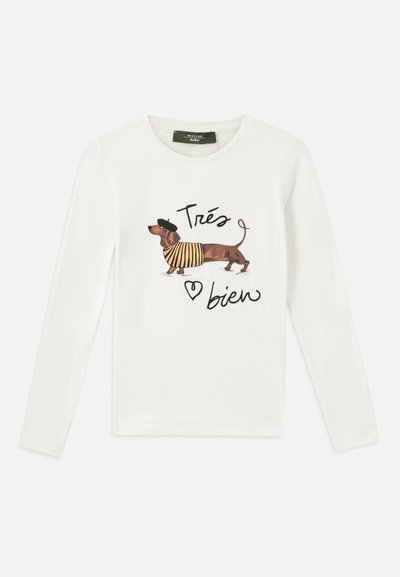 White long-sleeve shirt featuring a printed brown dachshund in a striped shirt and beret, with the text "Très bien" and a heart accent.