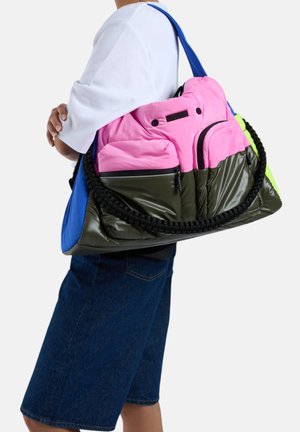 Un sac surdimensionné coloré avec des accents roses et verts, une base olive brillante, une bandoulière tissée et plusieurs compartiments dans un design unique.