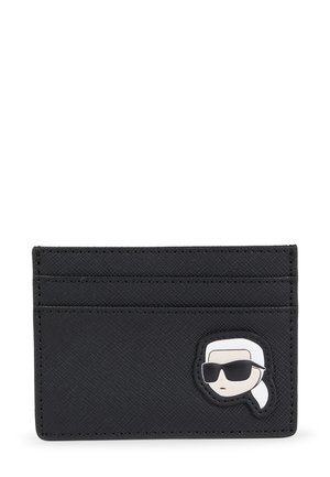 Porte-cartes noir texturé avec quatre fentes et un patch de visage de cartoon amusant portant des lunettes de soleil sur le devant. Matériel durable.