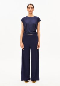 Marineblaues T-Shirt mit kurzen Ärmeln, kombiniert mit passenden Hosen mit weitem Bein. Der Stoff ist glatt und fließend, mit einem lockeren Schnitt.