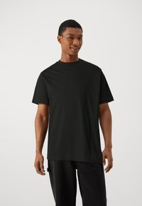 Black short-sleeve t-shirt with a crew neckline, crafted from soft fabric, featuring a relaxed fit and straight hem, worn with dark jeans.