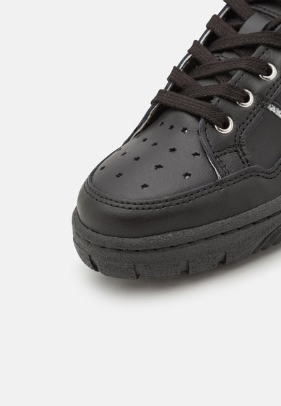 Sneaker in pelle nera con suola in gomma nera testurizzata, punta perforata con fori a forma di stella e lacci neri. Accenti argentati visibili.