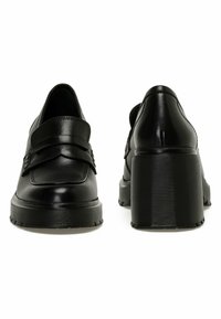 Czarne skórzane buty z okrągłym noskiem, szerokim paskiem i teksturowaną gumową podeszwą. Grubszy obcas dla dodatkowej wysokości i wsparcia.