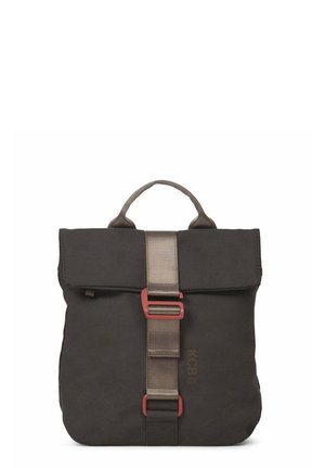 Mujer que lleva una mochila cuadrada gris oscuro con una correa y hebilla frontal, suéter beige y vaqueros azules, vista desde atrás.