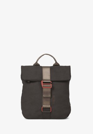 Mujer que lleva una mochila cuadrada gris oscuro con una correa y hebilla frontal, suéter beige y vaqueros azules, vista desde atrás.
