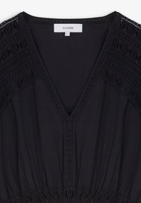 Robe noire à décolleté en V, avec des accents texturés et une couture élaborée aux épaules. Taille froncée et tissu lisse. Taille S.