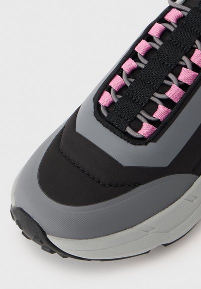 Black and gray sneaker featuring a textured surface, pink and gray laces, and a rounded toe with a thick sole for support.