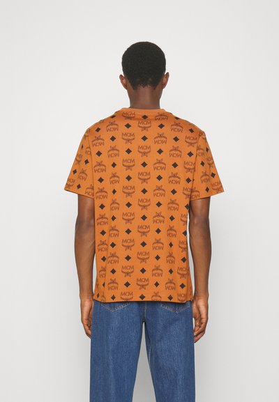 Kortärmad orange skjorta med ett upprepande svart mönster och diamantmotiv. Mjuk tygkvalitet med avslappnad passform, rund halsringning och korta ärmar.