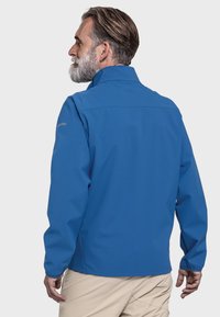 Blaue wasserdichte Jacke mit hohem Kragen, langen Ärmeln und elastischen Bündchen. Glatte Textur, dezentes Logo-Detail auf der Schulter.