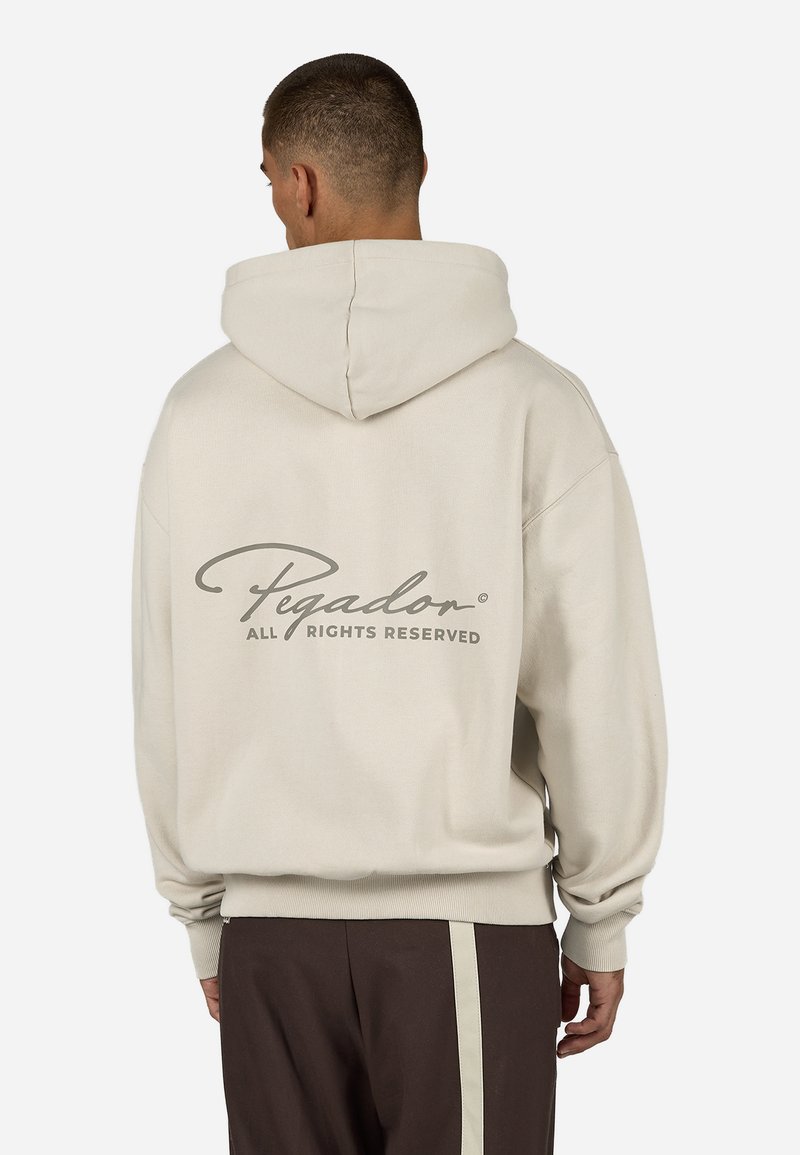 Kremfarget hettegenser med snøre i hetten, med en stor grå tekstlogo på baksiden. Mykt stoff med avslappet passform og klassisk design.