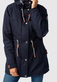 Granatowa kurtka z kapturem wykonana z wytrzymałej tkaniny, z dodatkami ze skóry, srebrnymi zatrzaskami, kontrastowymi ściągaczami oraz bocznymi kieszeniami.