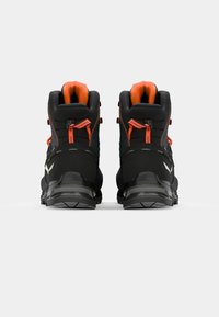 Black hiking boots with orange accents, reinforced heel, textured sole, and adjustable lacing, designed for durability and support.