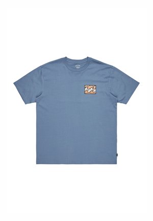 Blue cotton t-shirt with short sleeves, featuring a small square patch of wavy orange, cream, and black pattern on the left chest.