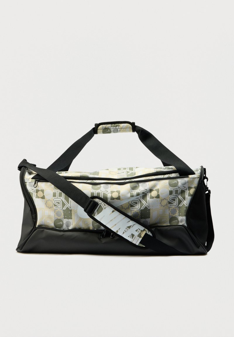 Μαύρη τσάντα duffel με γεωμετρικό ύφασμα σε πράσινο, κίτρινο και λευκό. Διαθέτει μαύρο λουράκι και επάνω λαβή για εύκολη μεταφορά.