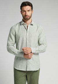 Hellgrün gestreiftes Button-Up-Hemd aus strukturiertem Stoff, mit Kragen und langen Ärmeln, kombiniert mit grünen Hosen.