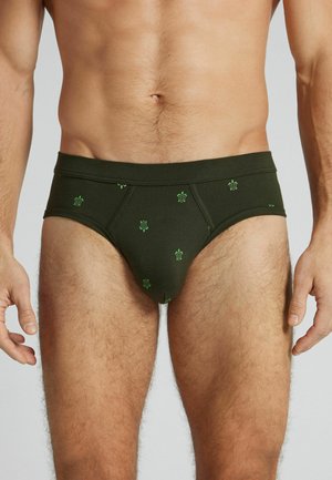 Mandlig torso iført mørkegrønne underbukser med små lysegrønne skildpaddeprint på en ensfarvet lys baggrund.