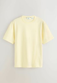 T-shirt en coton jaune pâle uni à manches courtes et col rond, taille moyenne avec petit logo brodé sur la poitrine.