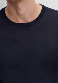 Granatowy bawełniany sweter z prążkowanym okrągłym dekoltem, o gładkiej teksturze i dopasowanym kroju, idealny na codzienne noszenie.