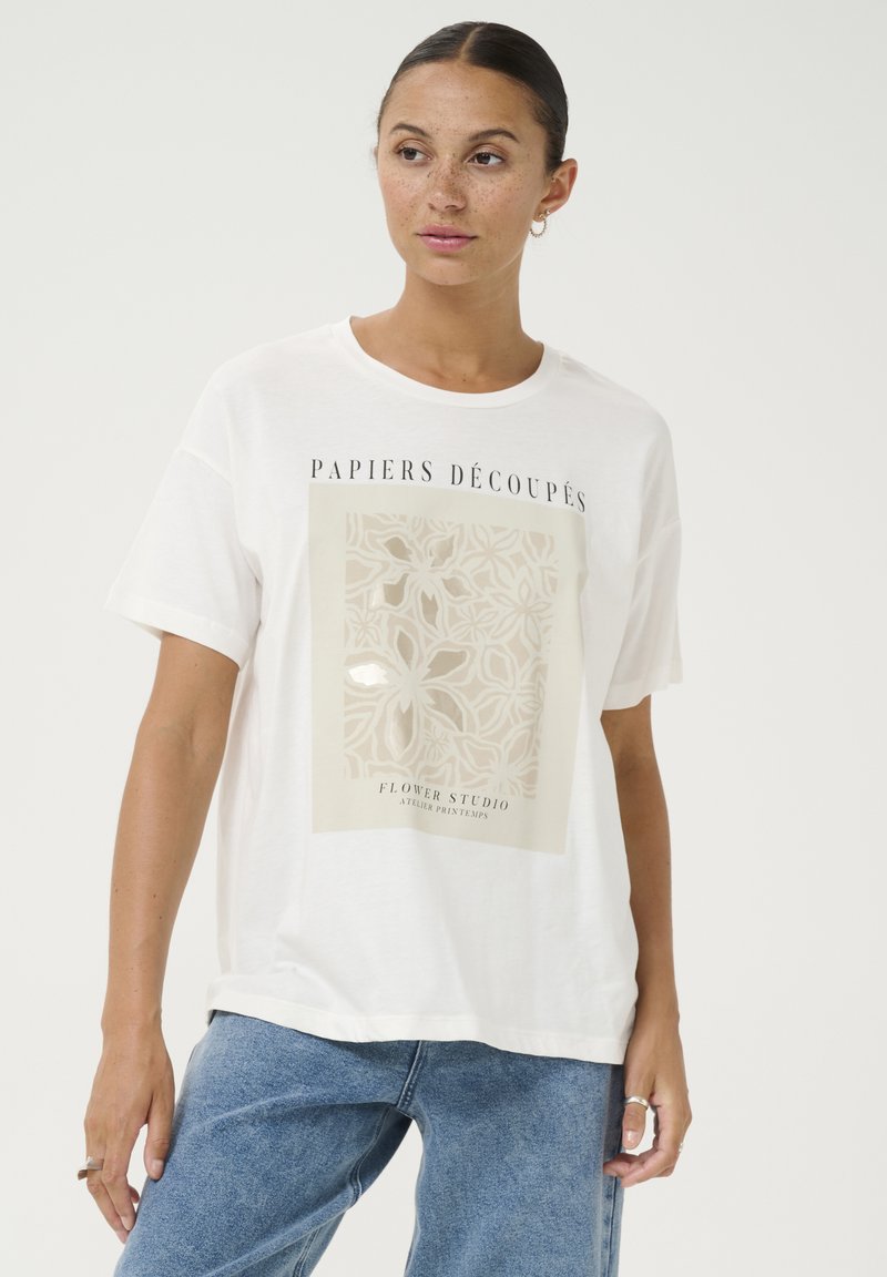 White cotton t-shirt with short sleeves, featuring a central graphic in beige with floral patterns and the text “PAPIERS DÉCOUPÉS” at the top.