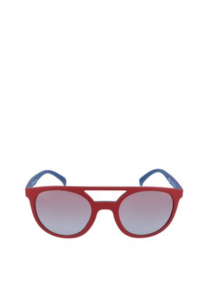 Occhiali da sole con montatura rossa, stanghette blu e lenti rotonde sfumate grigie, con un dettaglio caratteristico di taglio al ponte.