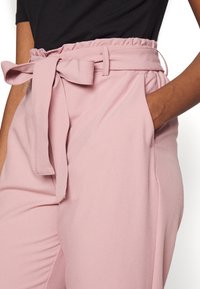 Lichtroze high-waisted broeken met een gerimpelde tailleband, een strikceintuur van stof, zijzakken en een gladde textuur.