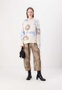 Adīts džemperis ar florālu rakstu krēmkrāsā, zilā un brūnā krāsā. Brūni rakstoti plaša stila bikses. Melnas augstpapēžu zābakus. Melna rokassoma.