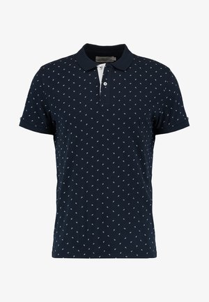 Navy polo shirt made of cotton, featuring a small white leaf pattern, a two-button placket, and short sleeves with rolled cuffs.