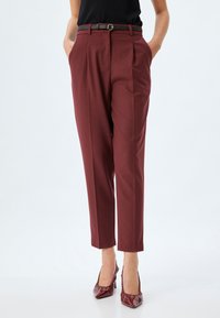 Burgunderfarbene maßgeschneiderte Hose mit hoher Taille, zwei Vorder- und einer schwarzen Gürtelschlaufe. Glattes Material mit einem eleganten, geraden Bein-Design.