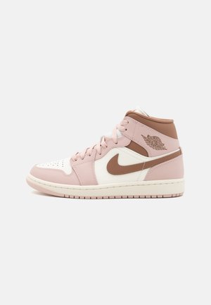 Højtop-sneaker i pink, hvid og brun med snørebånd, Nike swoosh og Air Jordan wing-logo på siden mod en ensartet baggrund.