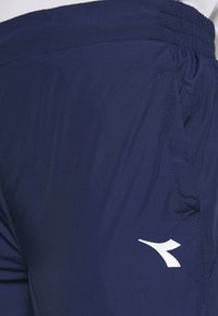 Námořnické sportovní šortky vyrobené z lehké tkaniny mají elastický pas a bílý logový akcent. Obsahují boční kapsu s bezšvovým šitím.