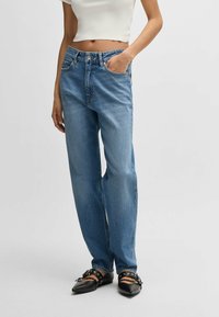 Ljusblå högmidjade jeans med rak benprofil, fem fickor och klassisk knapp- och dragkedjestängning. Distressad denimtextur.